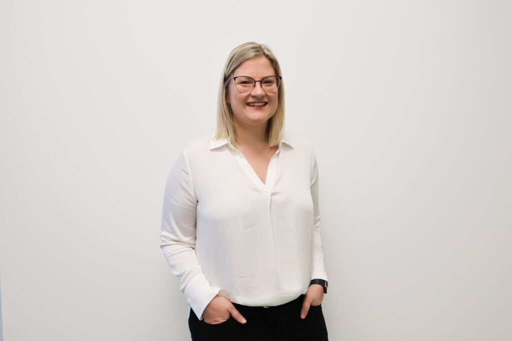 Eine Frau mit blonden Haaren steht vor einer Wand